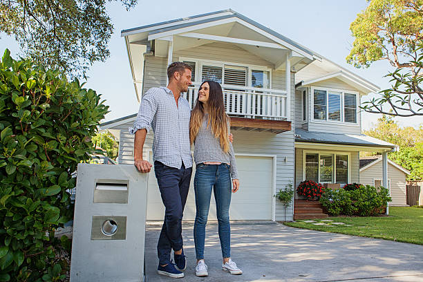 Happy couple standing outside their home after refinancing their mortgage and saving thousands with Broker Connect